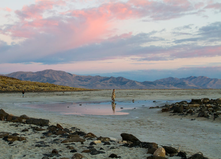A man walks on the dry lakebed of the Great Salt Lake at sunset.