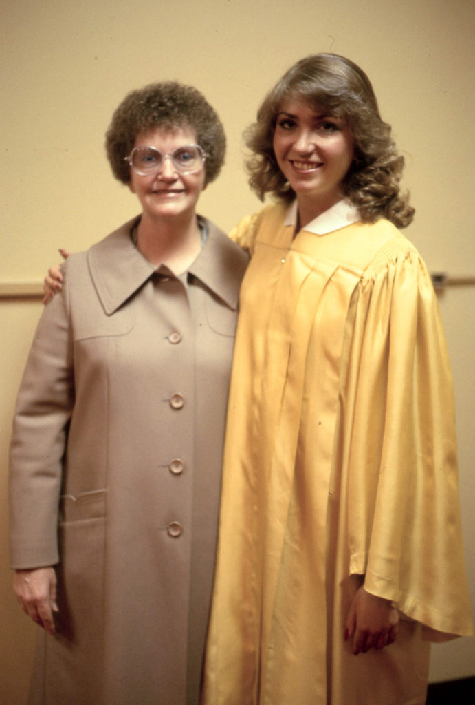 The author in graduation attire stands with her mother.