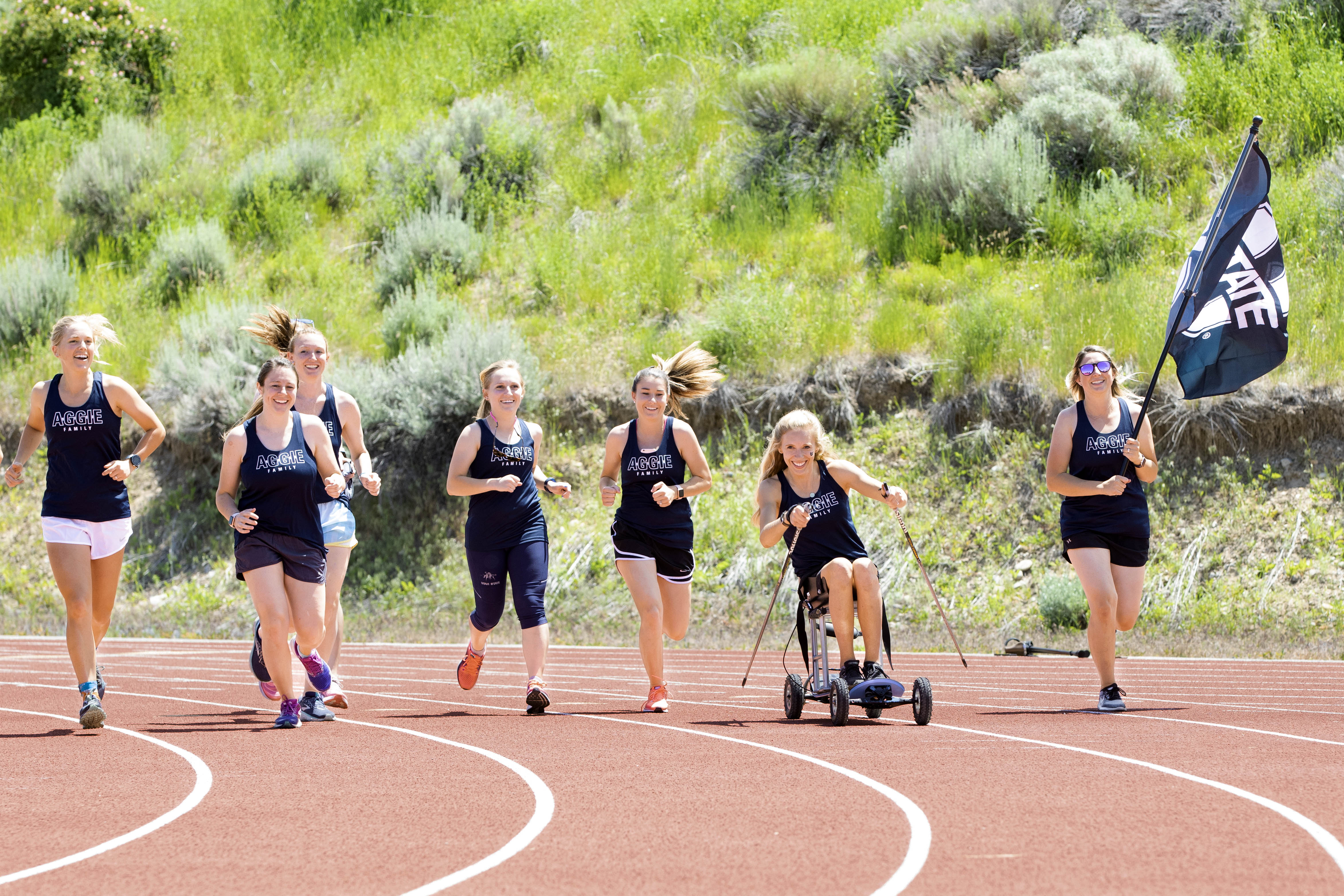 Former Members of the USU women's track team run around the track.