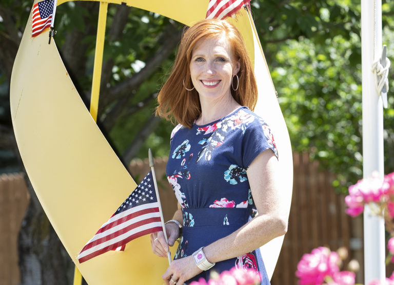 Jennie Taylor stands in her backyard holding an American flag.