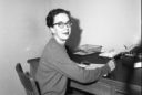 A kind looking woman smiles into the camera while sitting at her desk