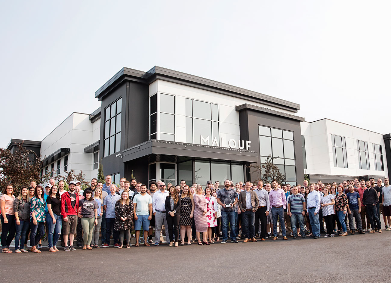 Malouf founders and the Logan-based employees stand outside the company's massive building in Nibley.