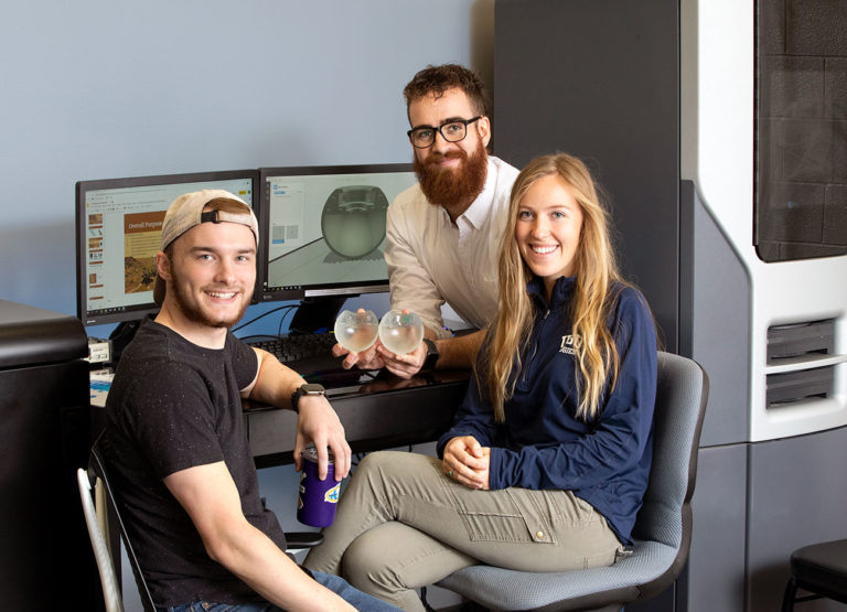 three students display their handheld device to help NASA detect life on Mars.