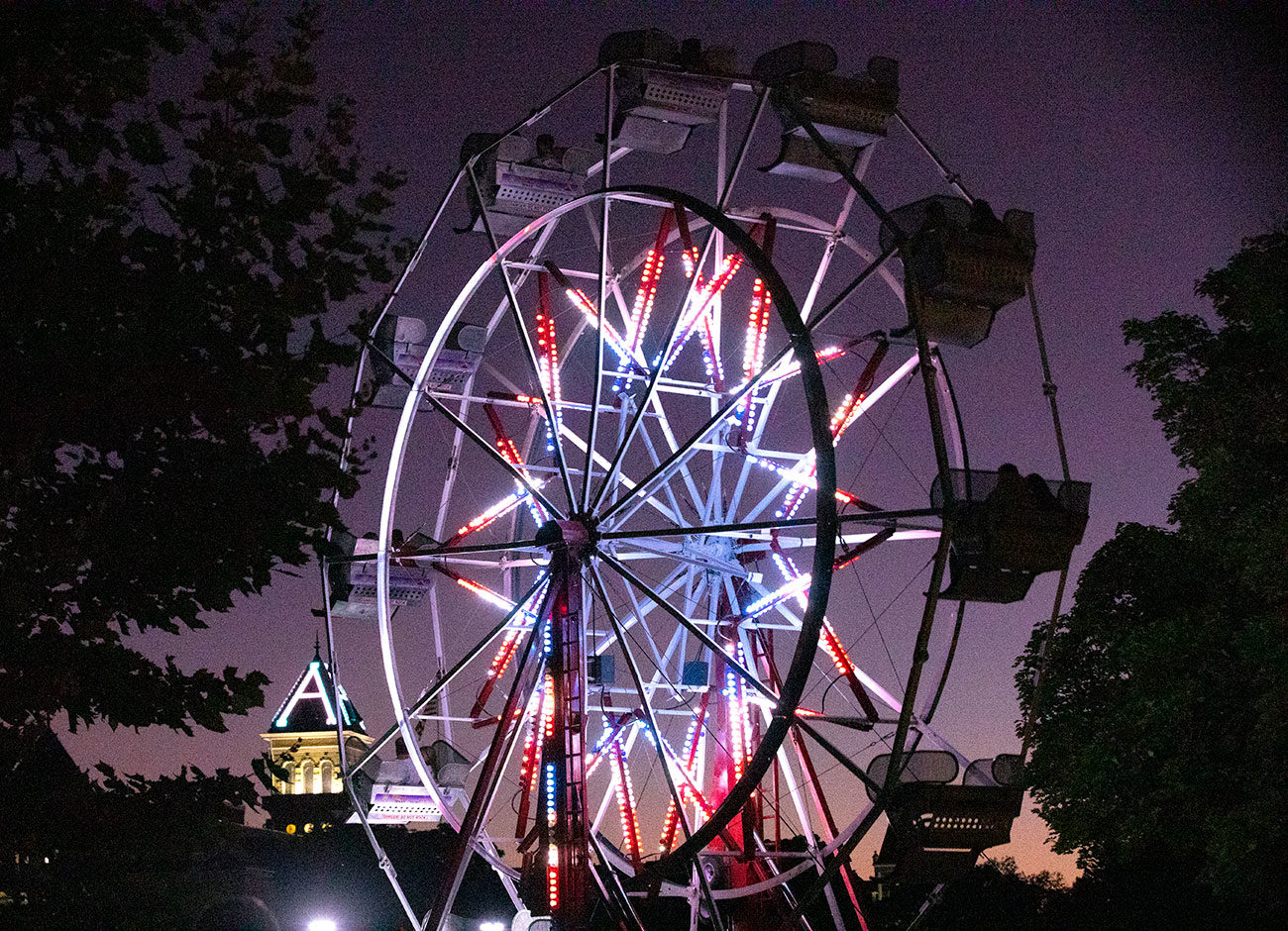 a ferris wheel glows red and blue in the night sky over the USU Quad