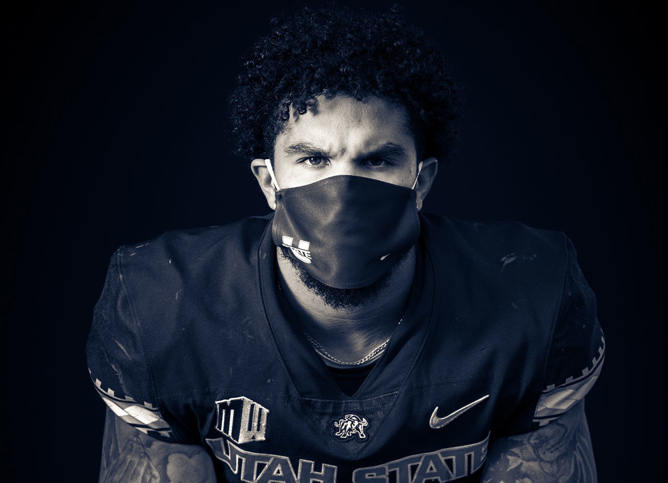 a college football player sits wearing a mask due to covid-19
