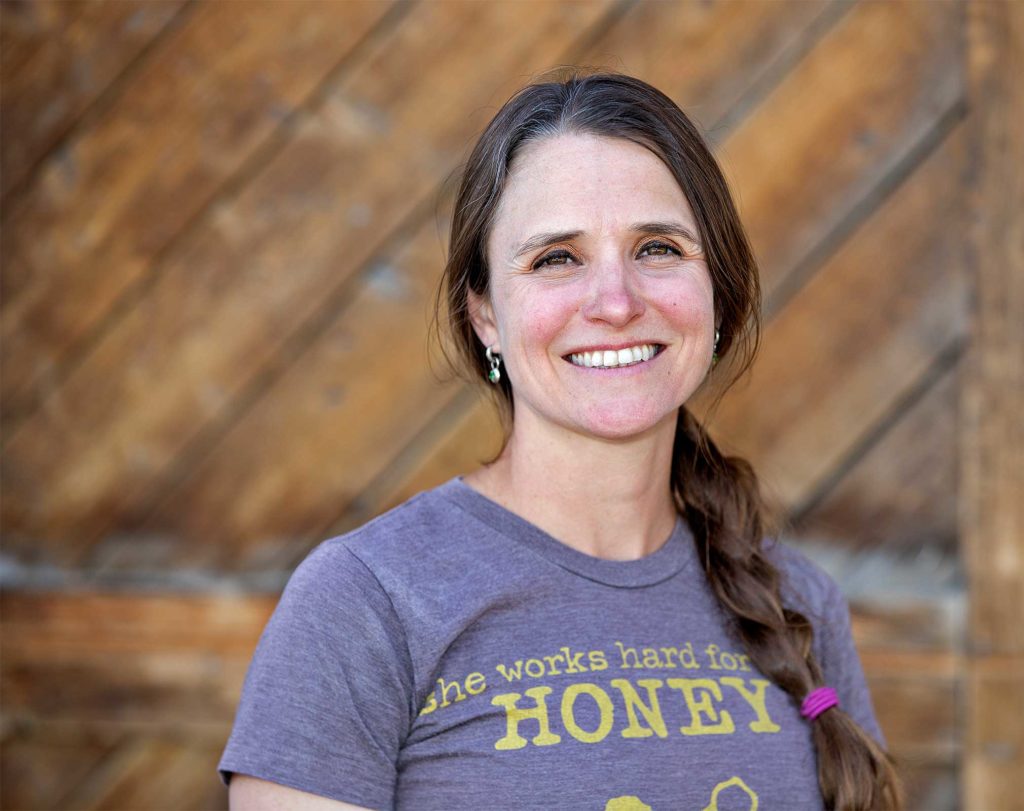 a portrait of the master gardener project lead katie wagner wearing a shirt reading "she works hard for the honey"