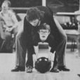 a black and white image of a USU student helping a child with special needs bowl