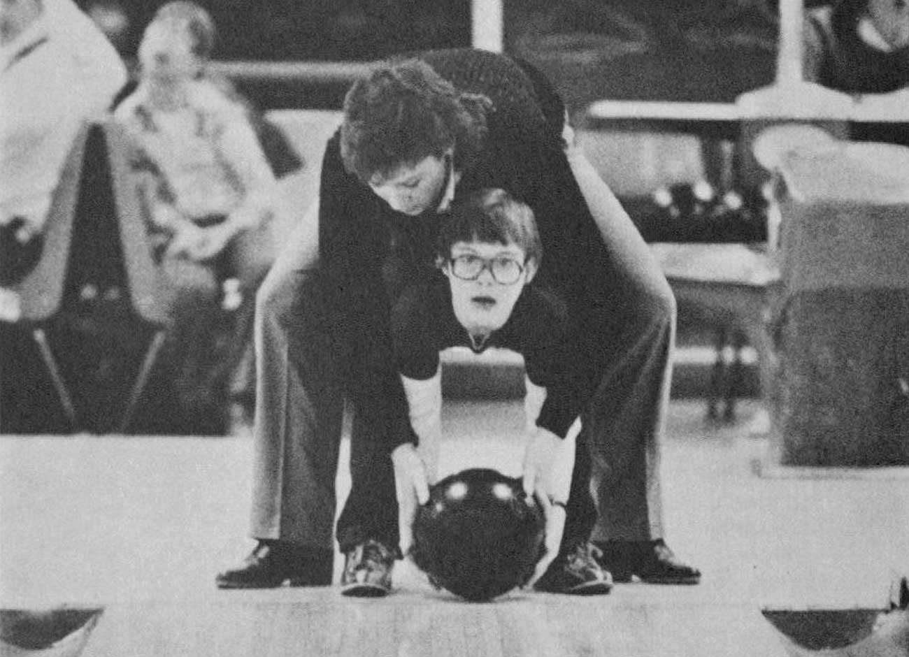 a black and white image of a USU student helping a child with special needs bowl