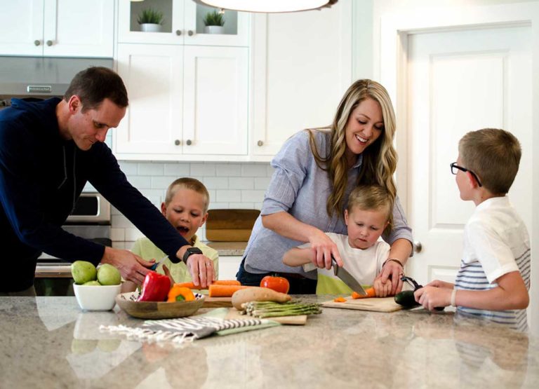 a family of five including two parents and three little boys prepares dinner in the kitchen