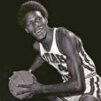 a young Black basketball player holds a ball dressed in his uniform