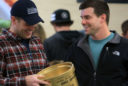 a man in a blue hat with the words USU College of Agriculture and Applied Sciences holds a crockpot spraypainted gold.