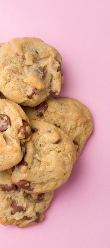 a pile of chocolate chip cookies sits on a pink piece of paper
