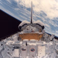 an image from space where Earth is visible in the background and the camera is trained on the back of the space shuttle