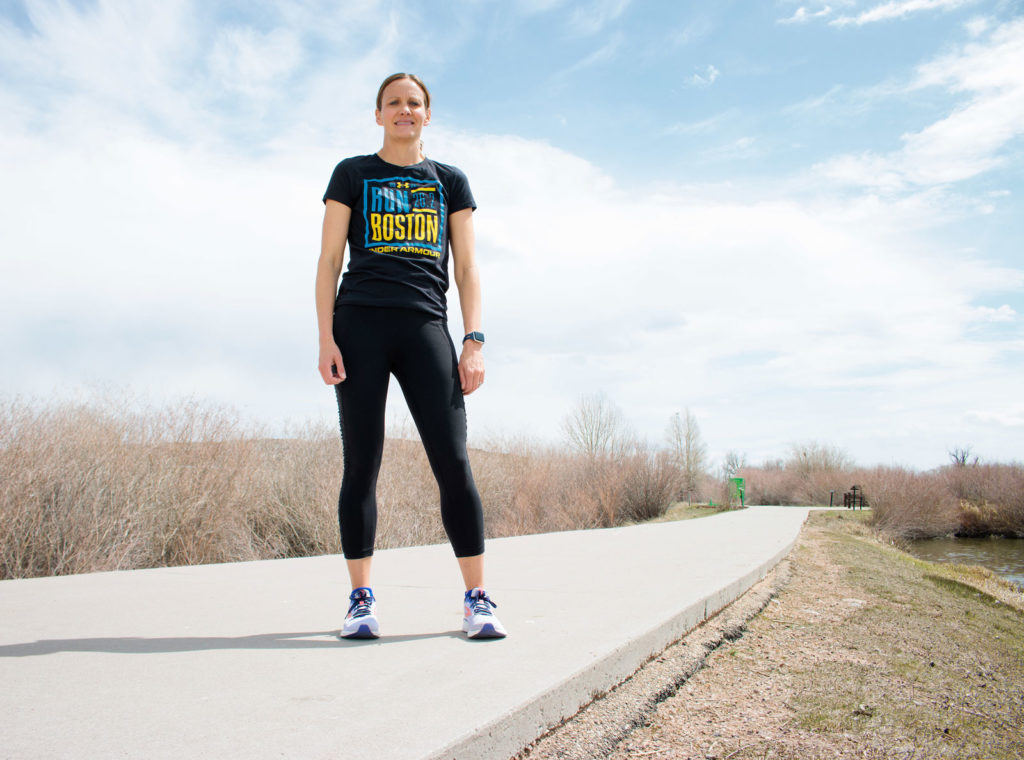 Runner Jenn Barker stands on a running path in a Boston Marathon t-shirt