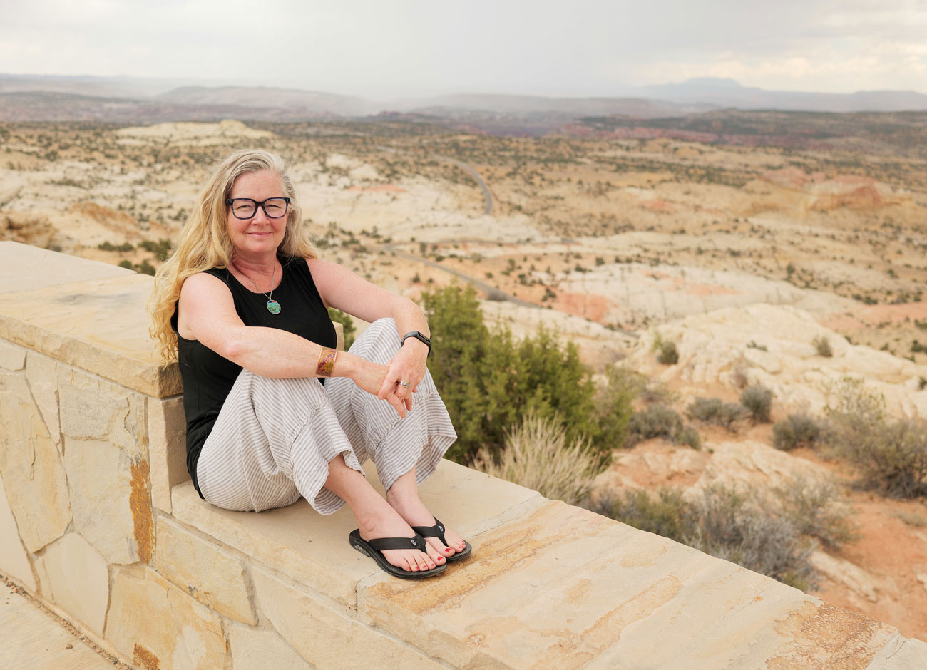 Allysia Angus sits on a stone overlook with Esacalante National Monument spreading out behind her