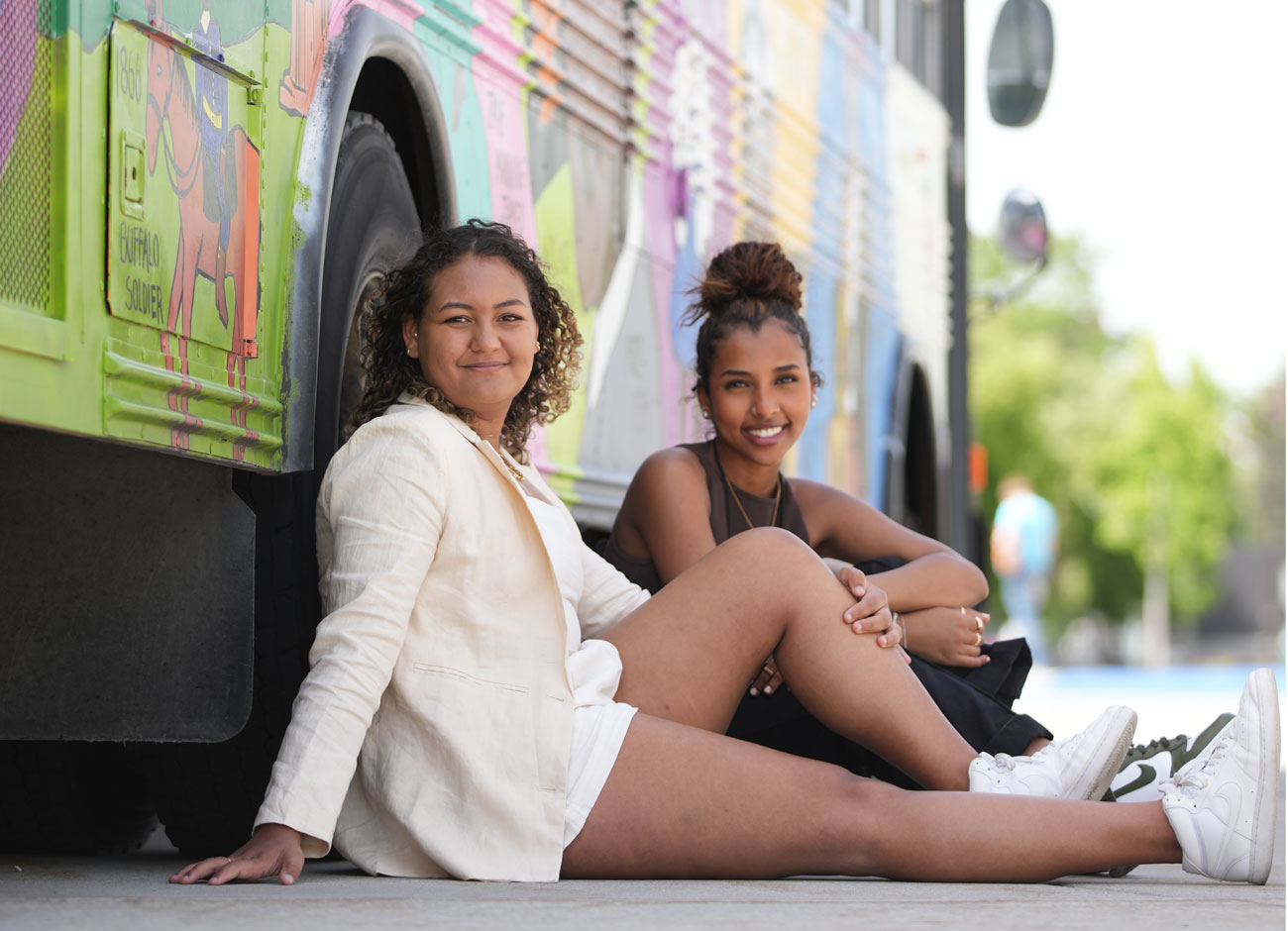 two young women lean against the Utah Black History Museum’s mobile exhibit