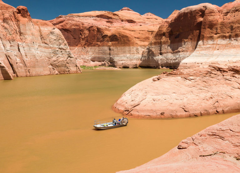 a small boat on Lake Powell with the infamous "bathtub ring" showing how water levels fluctuate over time
