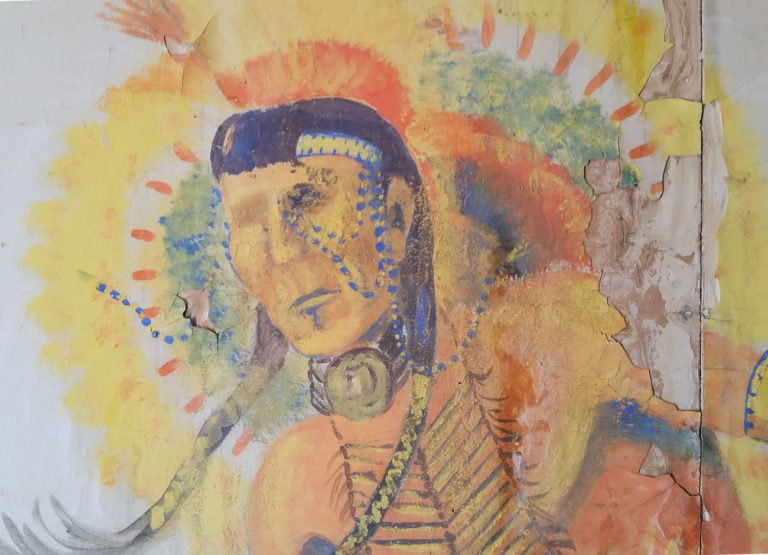 a chipped mural of a Native American warrior dancing