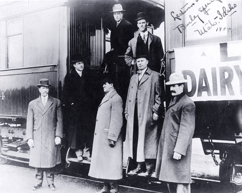 Black and white image of men near train.