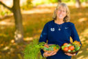 USU President Noelle Cockett holds baskets of vegetables from her garden.