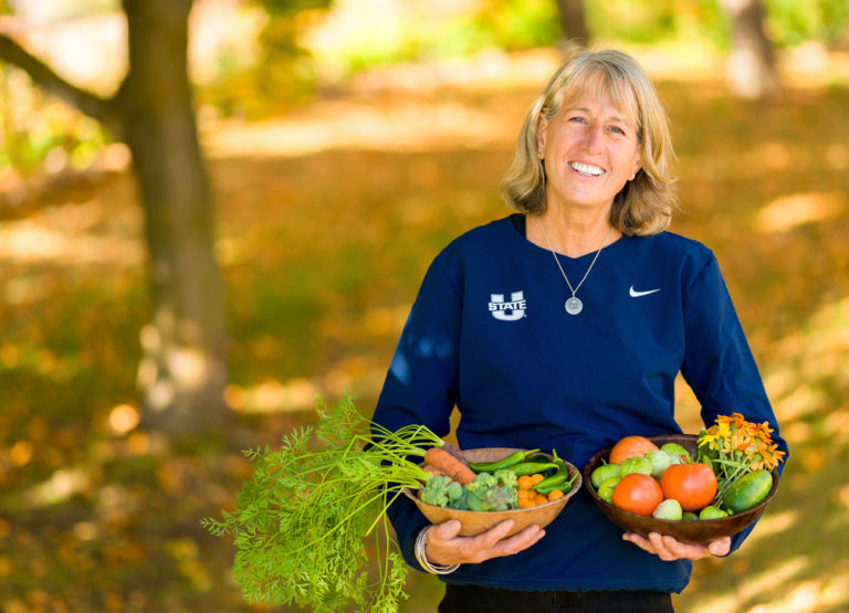 USU President Noelle Cockett holds baskets of vegetables from her garden.