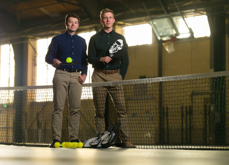 the founders of Bison Paddles stand in a gym with their pickleball paddles