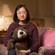 Researcher Yin Liu sits on a couch holding a teddy bear