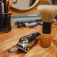 a close up of a barber's table featuring an electric buzzer and shaving brush
