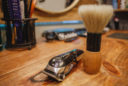 a close up of a barber's table featuring an electric buzzer and shaving brush