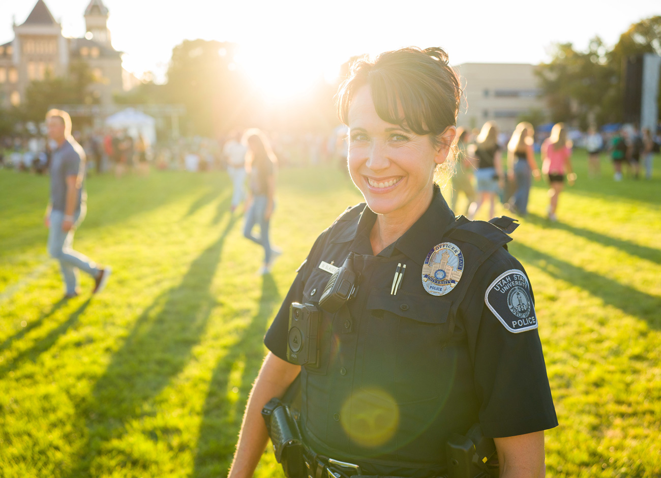 a female police officer smiles on the Quad with students in the background