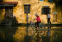an older woman bicycles through flooded streets