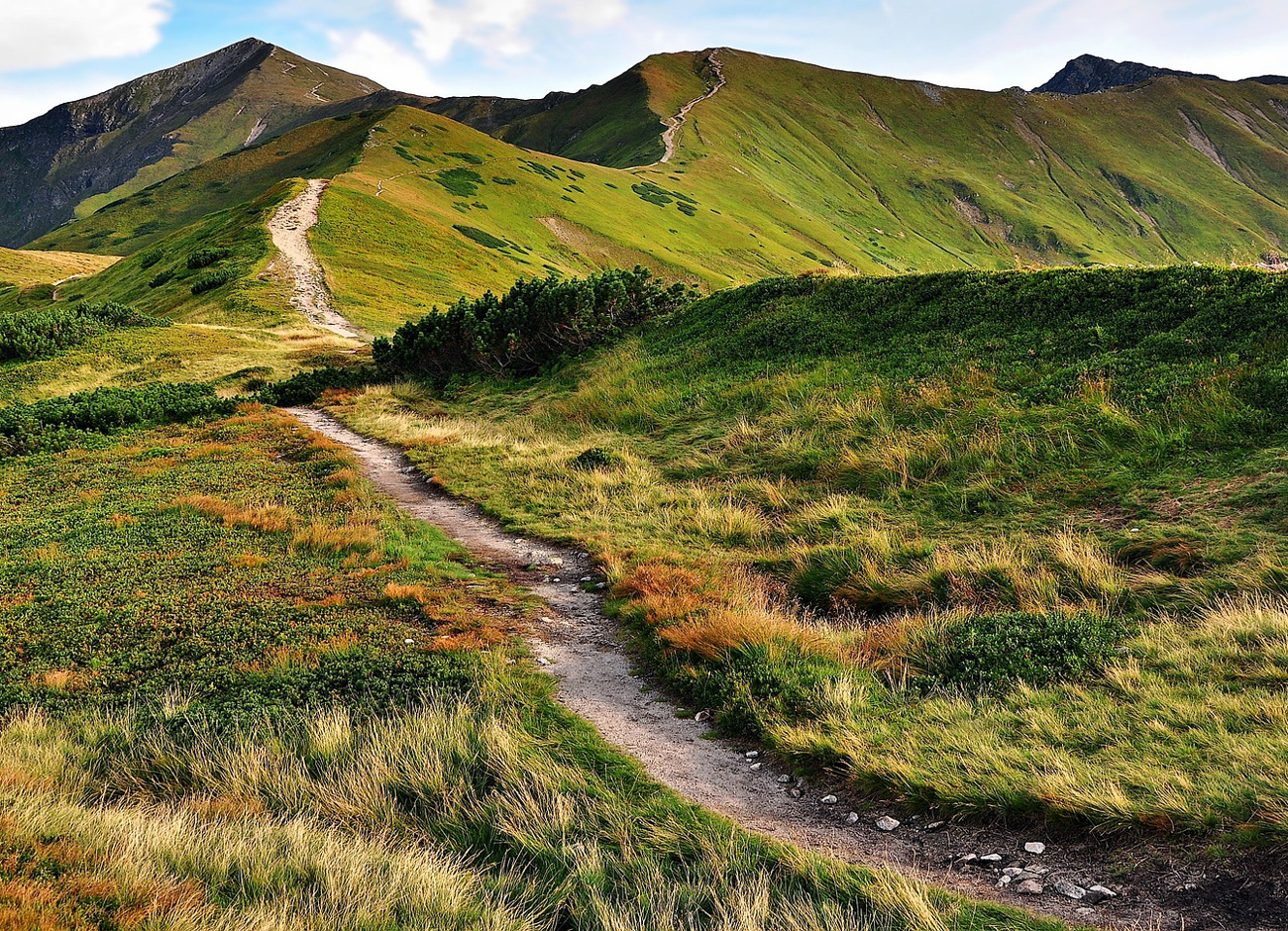 an empty trail traverses a mountainous landscape