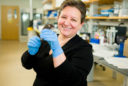 USU associate professor of psychology, Dr. Mona Buhusi, holds a mouse in gloved hands in her lab. Buhusi uses swimming mice to research cognitive decline.