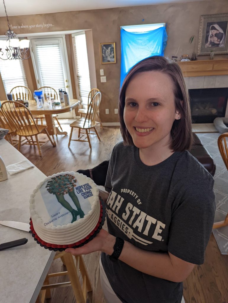Ashley Sheesley poses with a cake that reads, 'Congratulations on your diagnosis-versery' to commemorate her COVID-19 diagnosis. 
