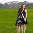 USU doctoral candidate Claudia Wright stands with her daughter in a green field with snowcapped mountains in the background.