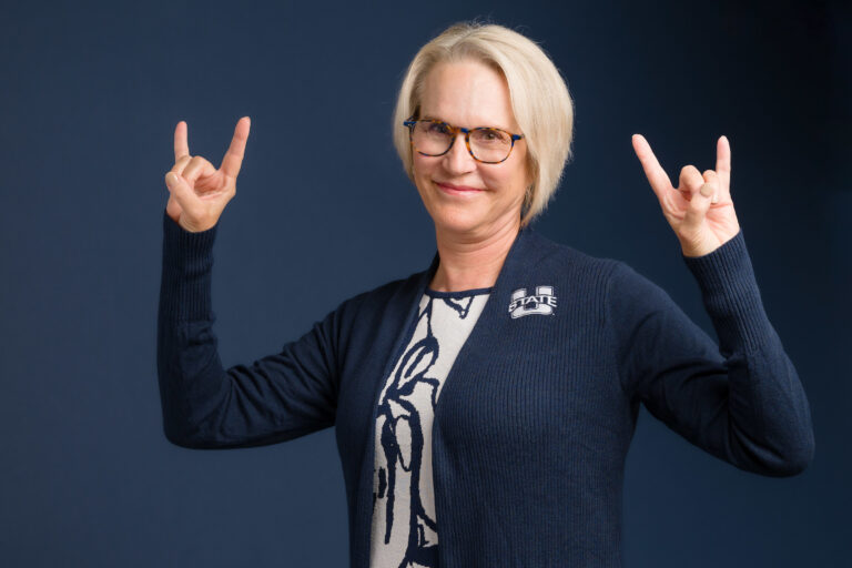 New USU president Elizabeth Cantwell throws up the horns to signify her Aggie spirit during a photoshoot.