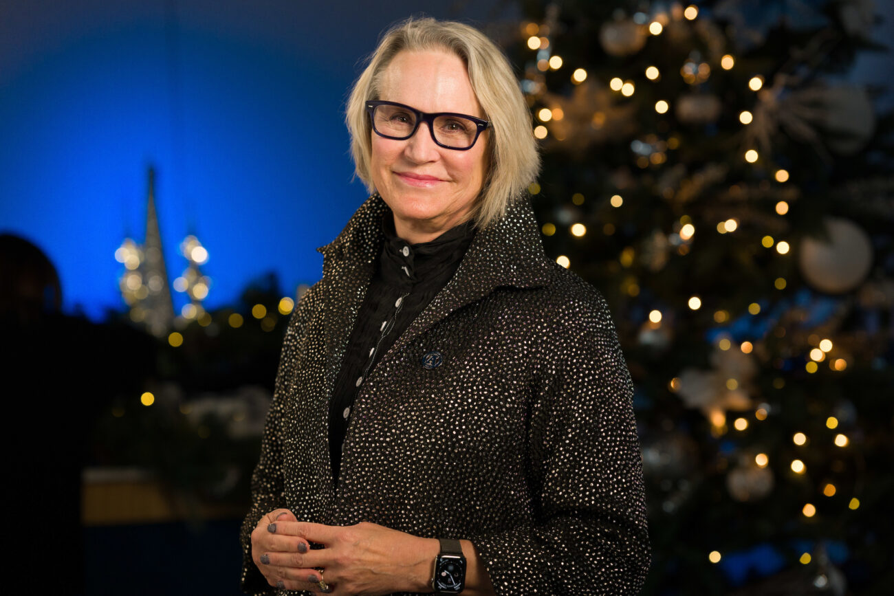 USU president Elizabeth Cantwell poses for a portrait in front of a lit Christmas tree.