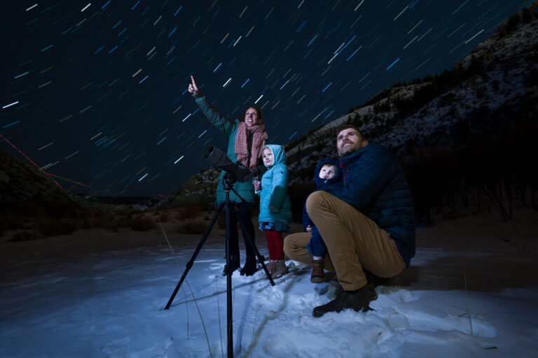 USU Researcher Chase Lamborn adjusts a spotting scope to look at the night sky with his family.