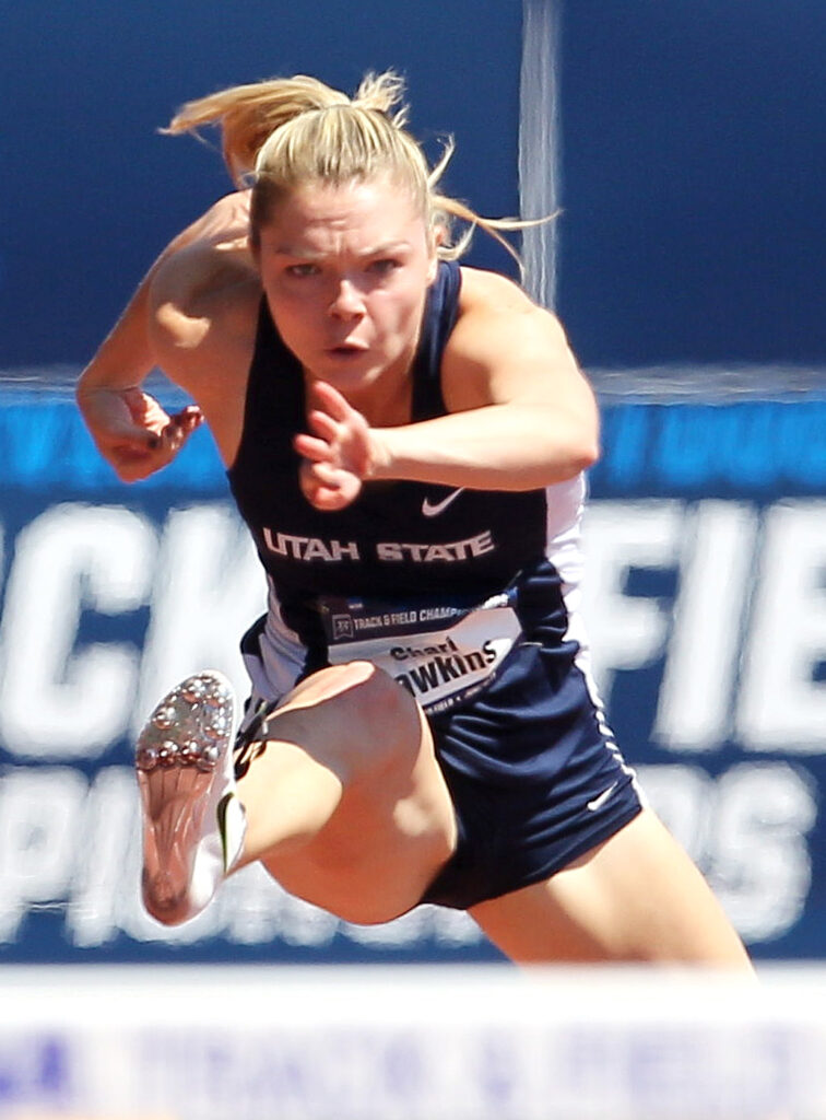 Chari Hawkins jumps over a hurdle while competing for Utah State University at the NCAA track and field championships.