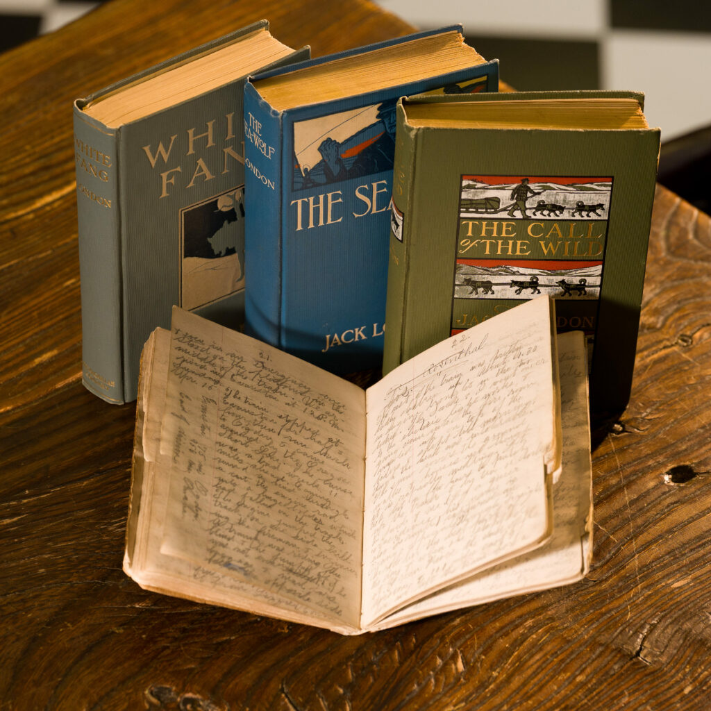 Four first-edition signed Jack London novels sit on a wood table.