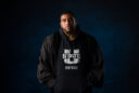 Bobby Wagner stands in a USU football hoodie with a commencement robe on.